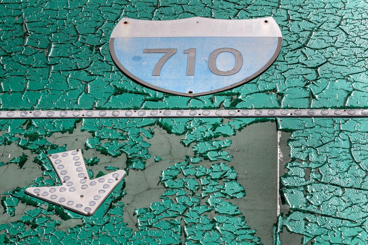 A sign for the Interstate 710 is covered in cracked green paint