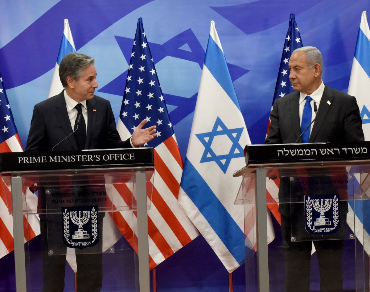 Secretary of State Antony J. Blinken and Israeli Prime Minister Benjamin Netanyahu stand side by side in front of flags.