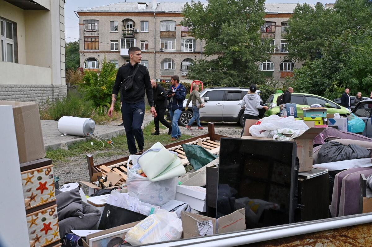 Household furniture and other belongings are collected in a yard as people walk about