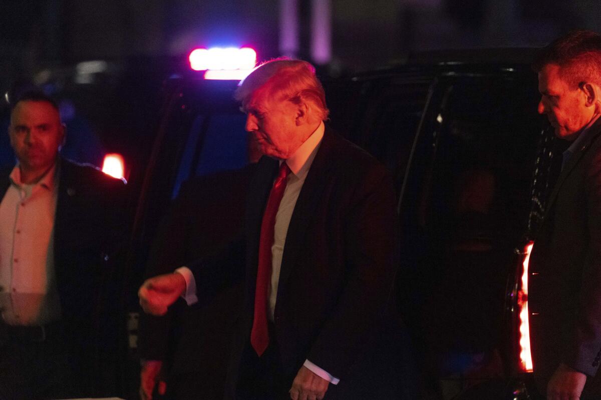 Former President Donald Trump exiting a car at night, with security.