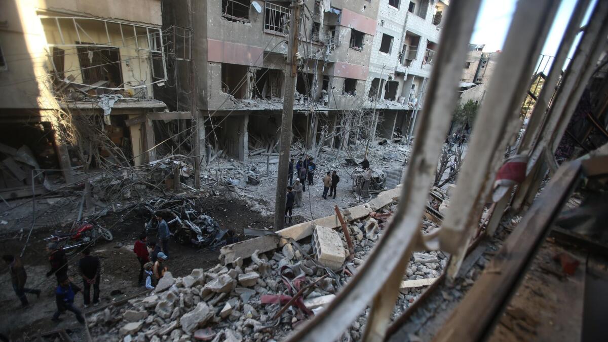 People inspect damaged buildings in Douma, Syria, after an airstrike by Syrian government forces on April 7.