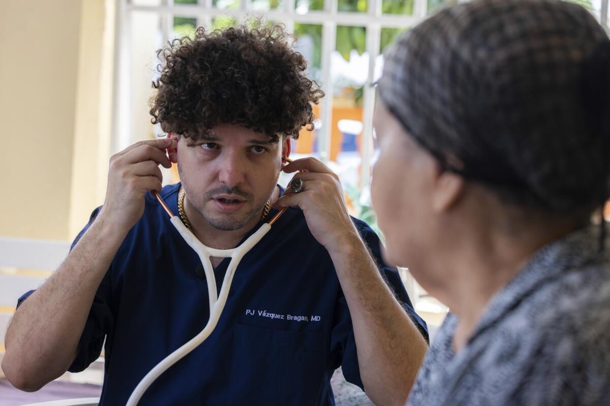 Dr. Pedro Juan Vázquez, better known by his stage name PJ Sin Suela, attends to a patient in Loiza, Puerto Rico.