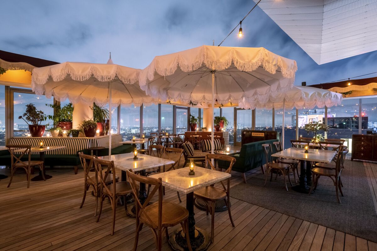A rooftop bar with white frilly table umbrellas