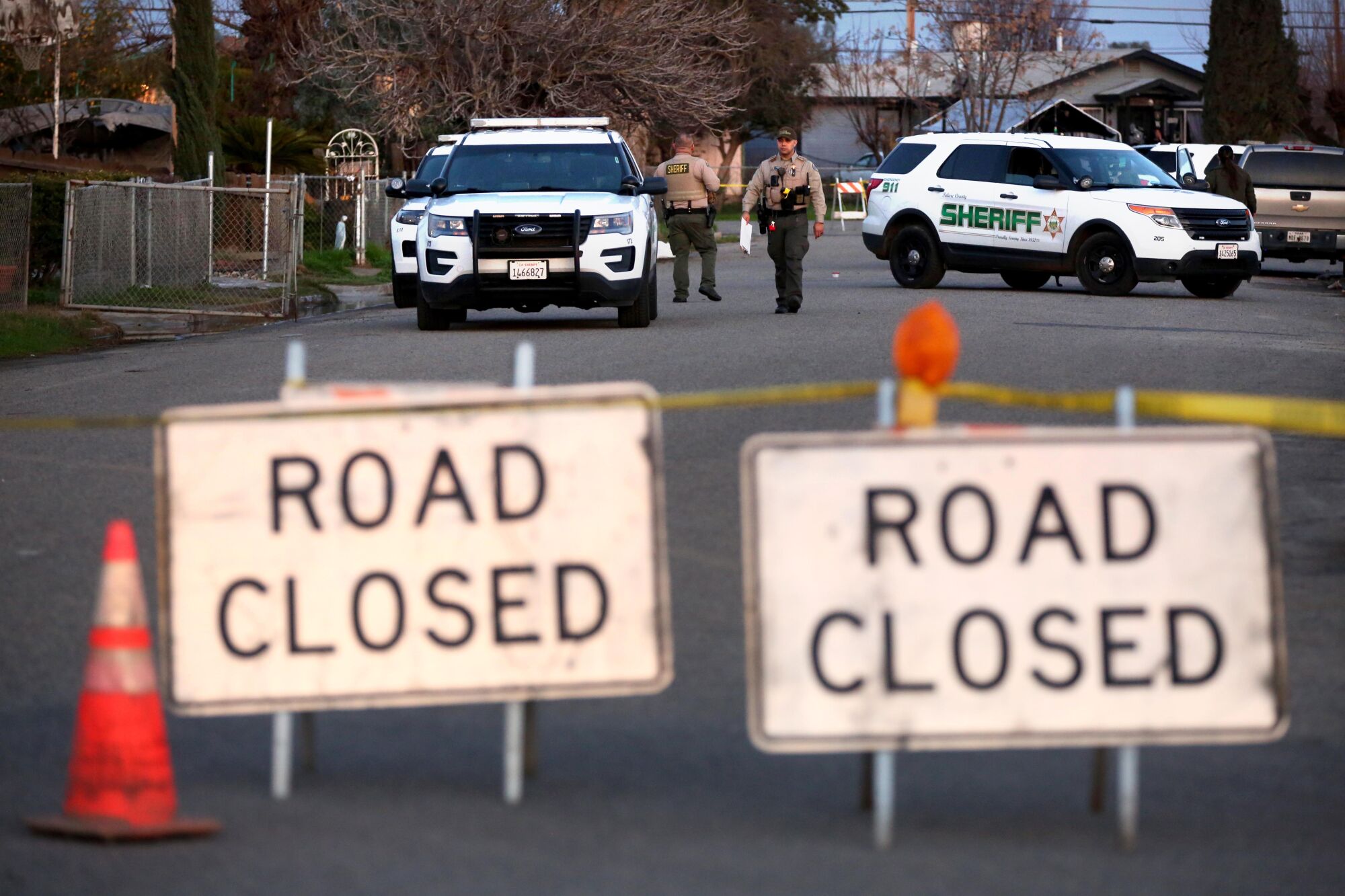 Deputies standing beside department vehicles on a residential street with "Road Closed" signs
