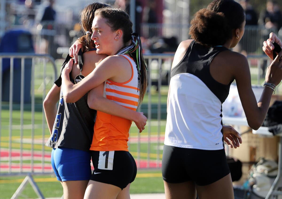 Huntington Beach's Makenzie McRae hugs her opponents after winning the girls' 3,200-meter race on Saturday.