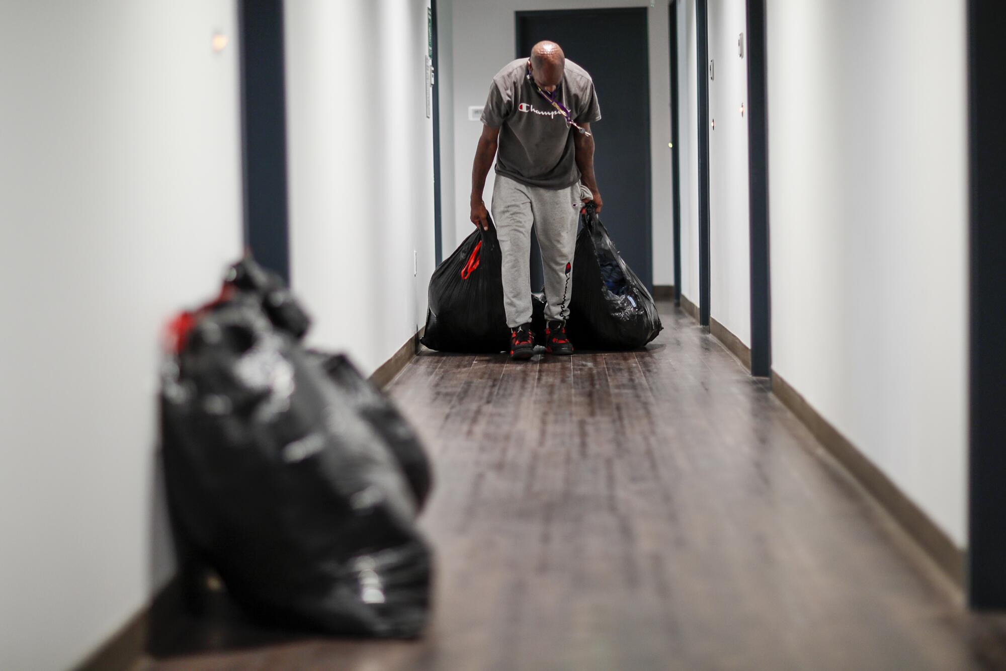 Donald Winston drags his belongings along the hallway as he moves into his new home at the Hartford Villa Apartments.