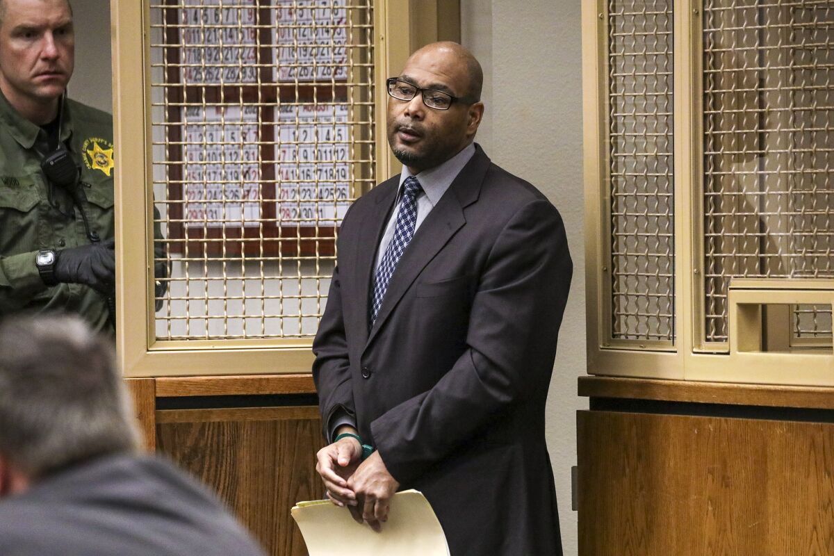 A man in a suit stands in a courtroom