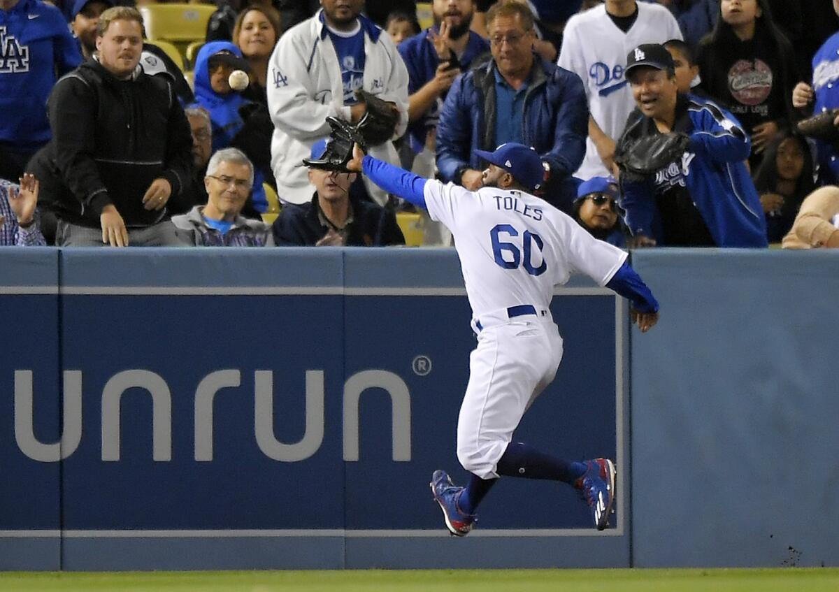 Andrew Toles tries to make the catch before crashing into the fence and hurting his knee.