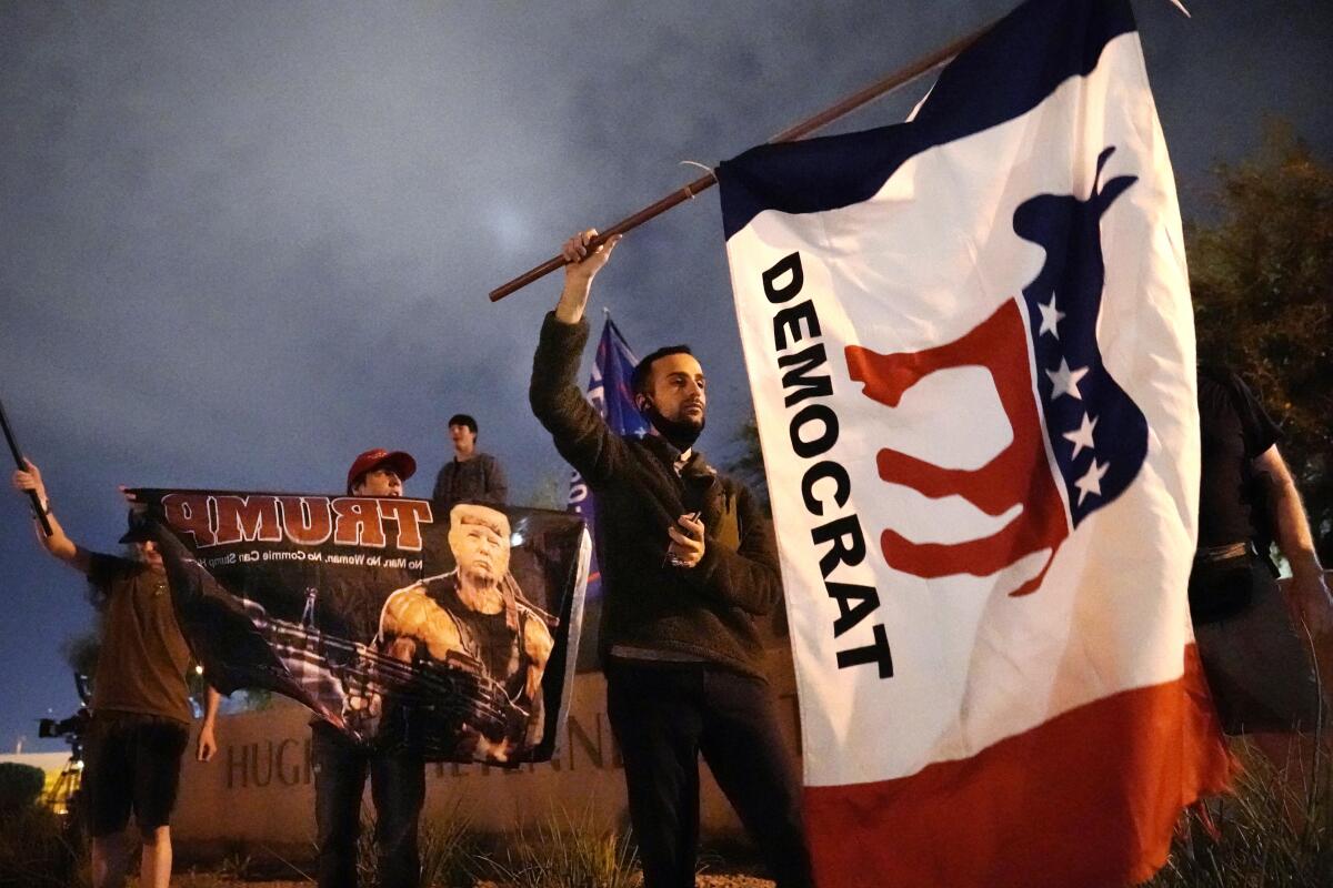 A supporter of Joe Biden waves a flag in front of the Clark County Election Department in Las Vegas.