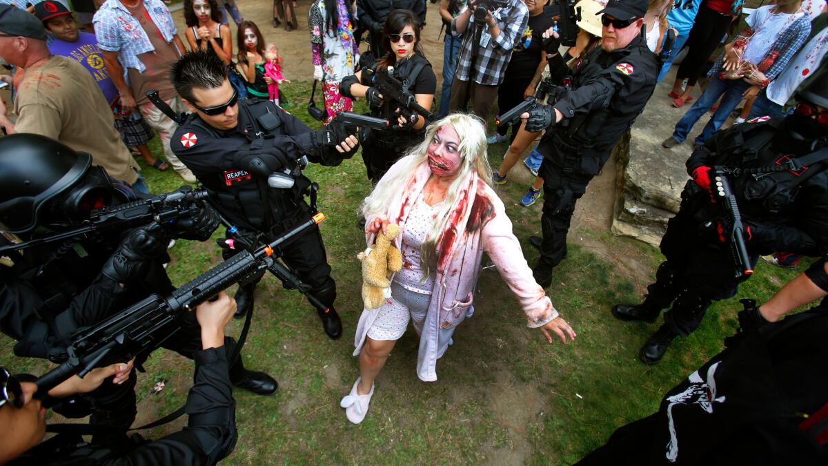 Role-playing hunters trap "zombie" Jennifer Cooper, center, in 2013 during the seventh annual Zombie Walk at Comic-Con in San Diego.