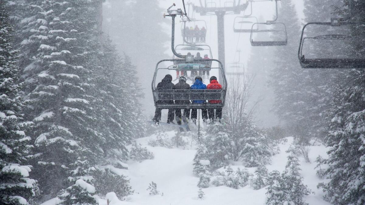Skiers at Northstar California ride a chairlift through heavy snowfall. 