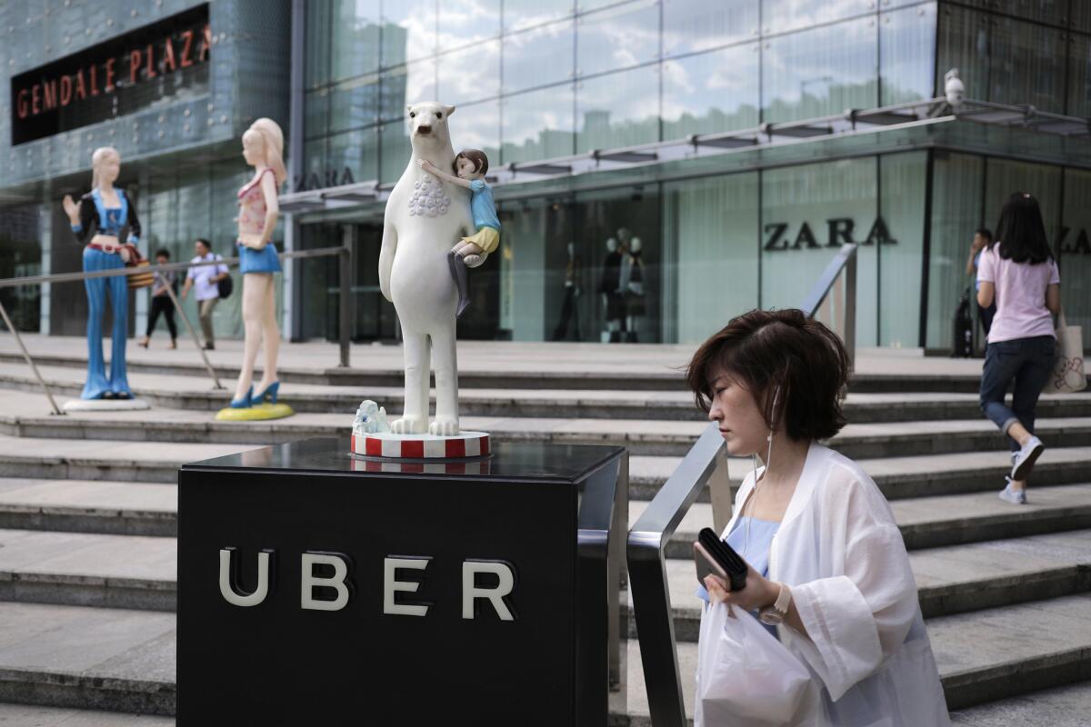 A woman walks past an Uber station outside a shopping mall in Beijing on Aug. 26. China's anti-monopoly regulators are reviewing the proposed merger of Uber Technology Ltd.'s Chinese operations with its biggest local competitor in the ride-hailing market.