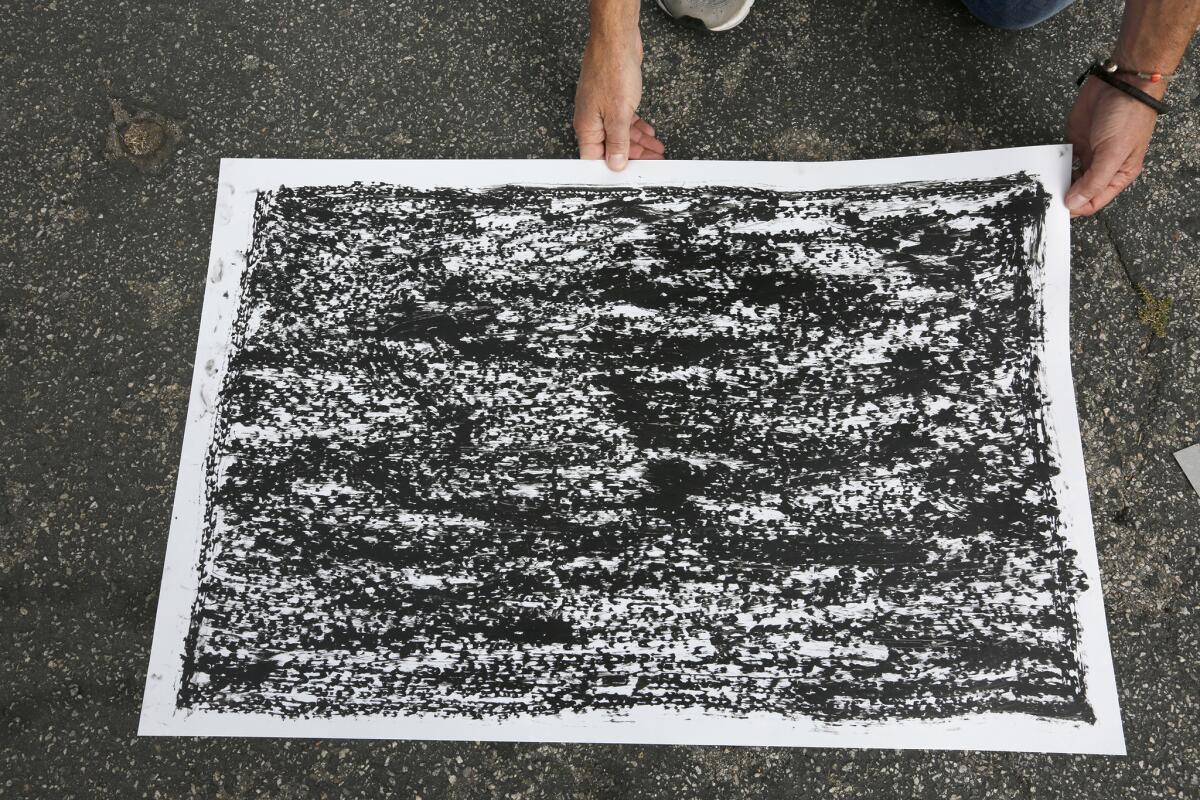 Artist Jeff Beall displays a rubbing taken at the site of an unsolved death related to the 1992 L.A. riots in Greenwood Meadows.