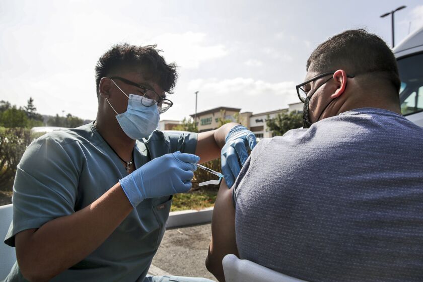 Diamond Bar, CA - September 29: Alan Antolin, left, administers J&J COVID-19 vaccine to Steven Katz at mobile clinic set-up by McDonald's and the California Department of Public Health in the parking lot behind McDonald's on 205 block of Diamond Bar Blvd. on Wednesday, Sept. 29, 2021 in Diamond Bar, CA. (Irfan Khan / Los Angeles Times)