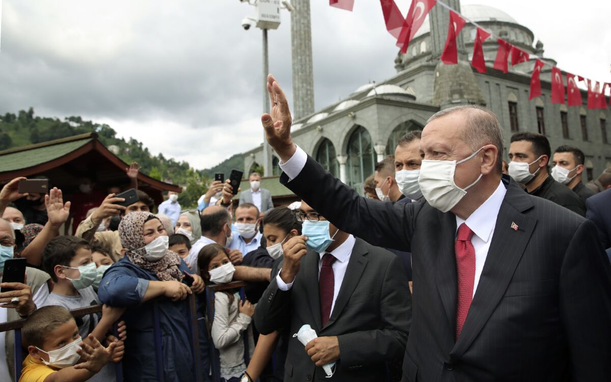 Turkey's President Recep Tayyip Erdogan wearing a face mask to protect against the spread of coronavirus, waves toward his supporters in Black Sea city of Rize, Turkey, Saturday, Aug. 15, 2020. Turkey's health minister says the number of new COVID-19 infections Saturday has hit its highest in 45 days and announced 1,256 new cases.(Turkish Presidency via AP, Pool)