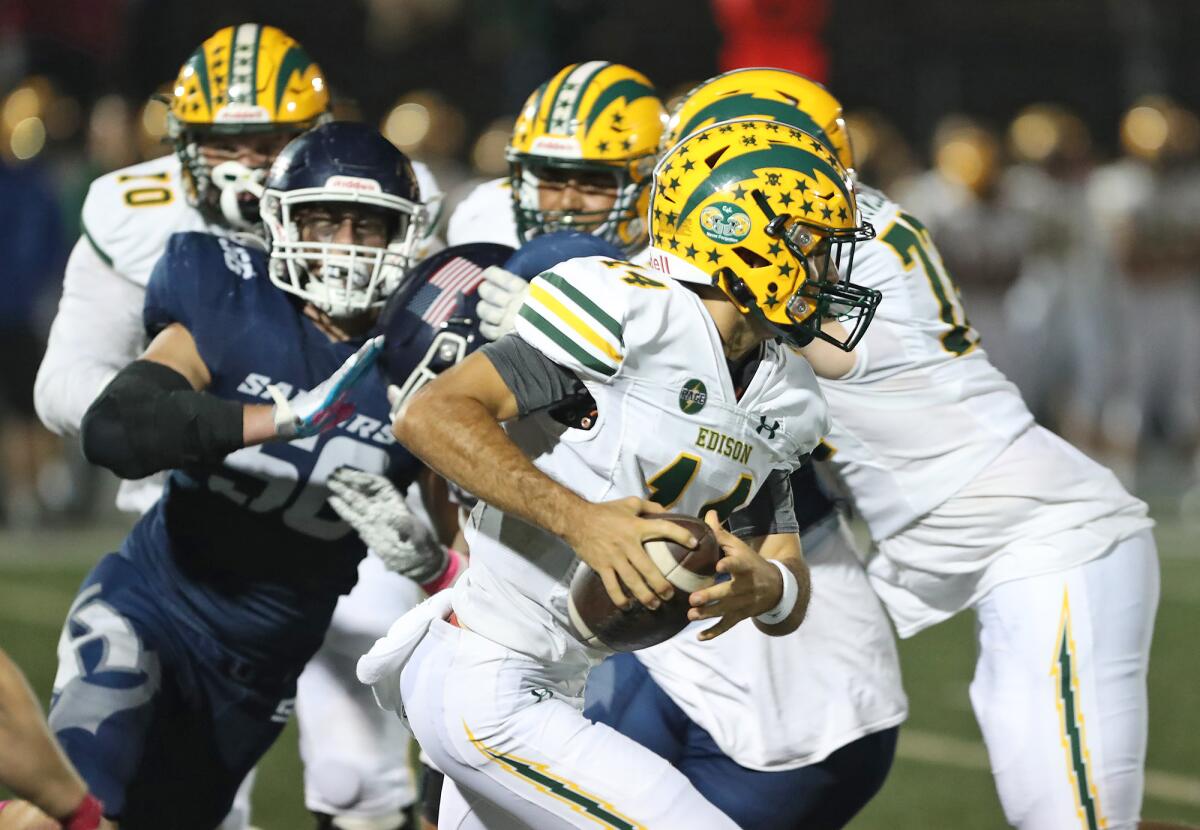 Edison quarterback Parker Awad (14) is forced from the pocket during a Sunset League football game against Newport Harbor.