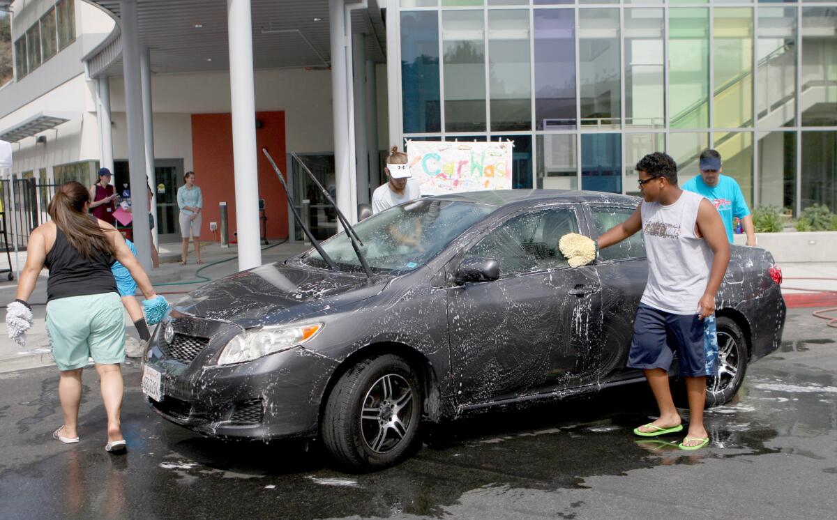 Volunteers wash cars during a fundraiser at College View School in Glendale on Tuesday, June 28, 2016. Money raised will be used for specialized programs for the school's disabled students.