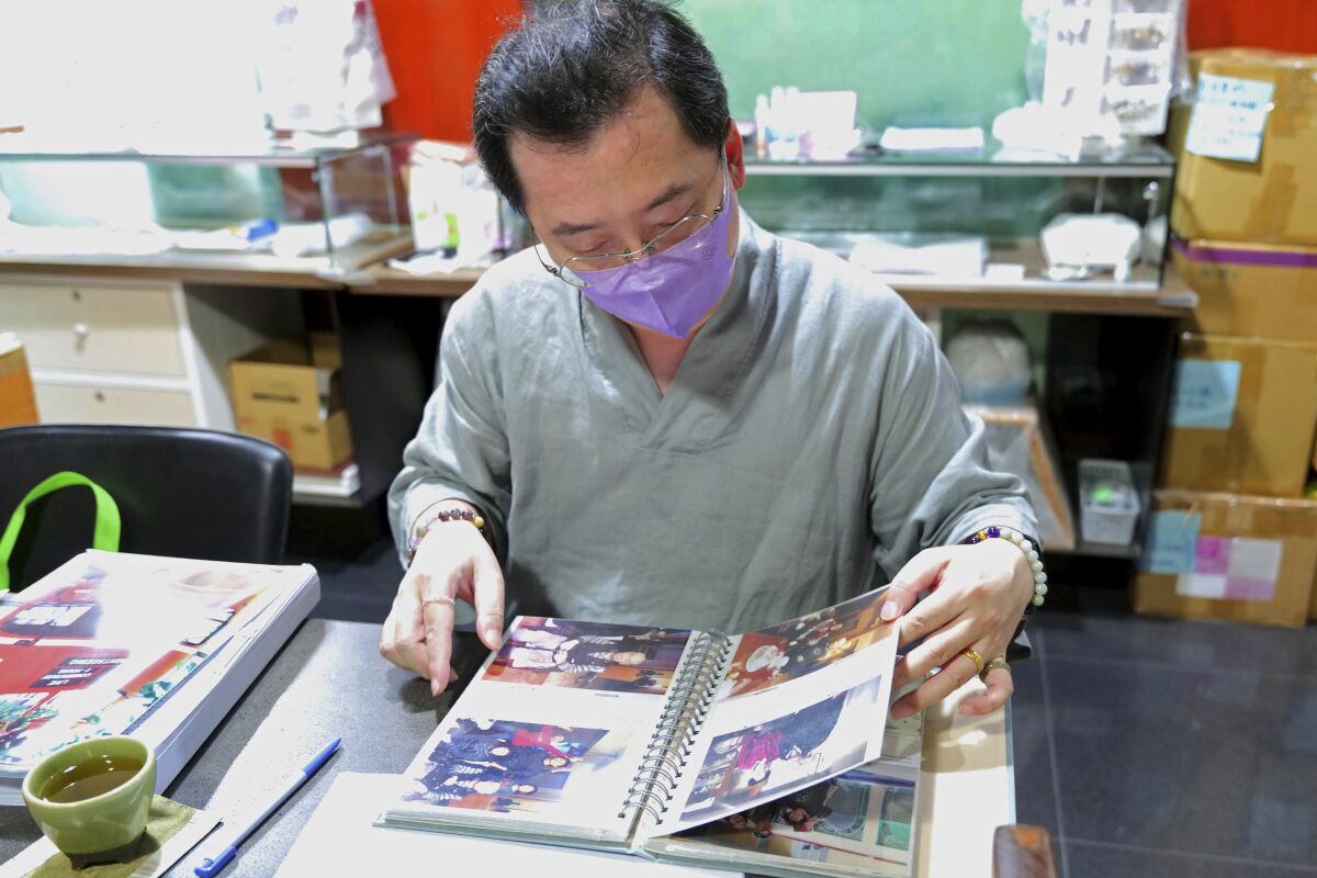 Adams Chi, a member of a group of Taiwanese who lose loved ones to COVID and are seeking compensation from the government, looks at photos of his parents during an interview on Sept. 23, 2021, Taipei, Taiwan. The island is hailed globally as a pandemic success story. But for Chi and other families who lost loved ones, they are angry that their government did not prepare enough and they don't believe it's a success. (AP Photo/Huizhong Wu)