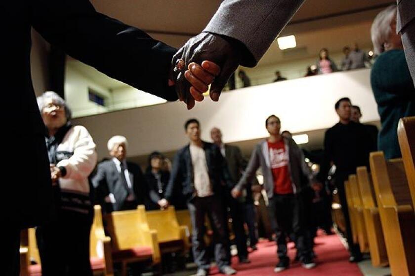Mourners hold hands in during a vigil for victims of the Oikos University shootings at Oakland's Allen Temple Baptist Church on Tuesday.