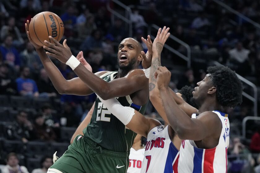 Milwaukee Bucks forward Khris Middleton (22) attempts a layup as Detroit Pistons center James Wiseman, right, and guard Killian Hayes defend during the first half of an NBA basketball game, Monday, March 27, 2023, in Detroit. (AP Photo/Carlos Osorio)
