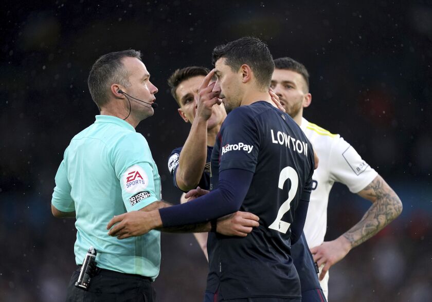 Referee Paul Tierney looks at Burnley's Matthew Lowton after he was hit on the head with a bottle thrown from the stands , during the English Premier League soccer match between Leeds United and Burnley, at Elland Road, in Leeds. England, Sunday, Jan. 2, 2022. (Mike Egerton/PA via AP)