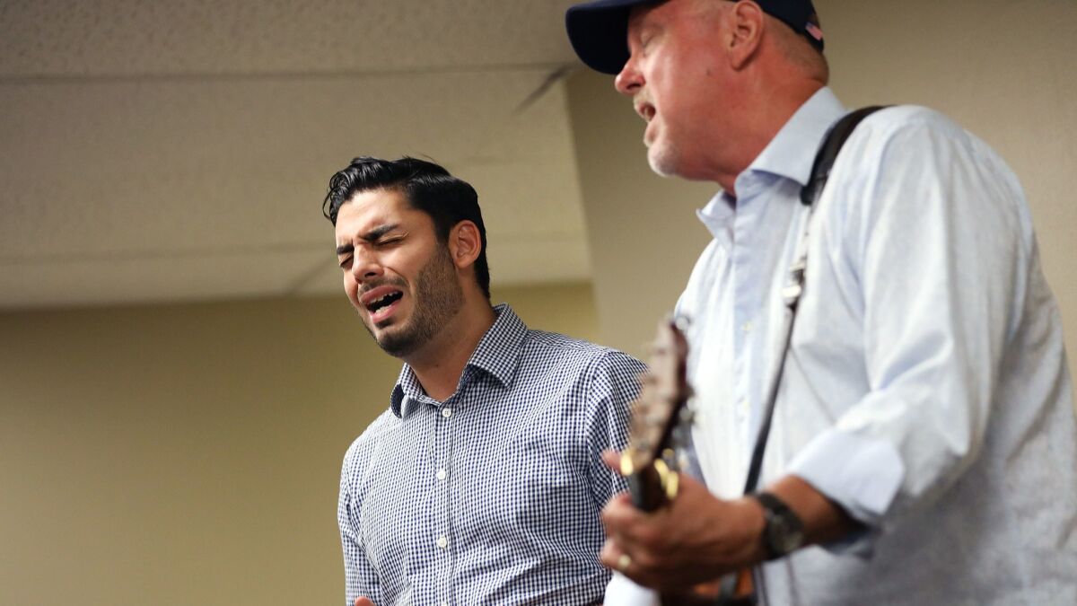 Ammar Campa-Najjar, left, sings with his former philosophy professor and friend Peter Bolland, right, during a La Jolla Democratic Club meeting Sept. 9.