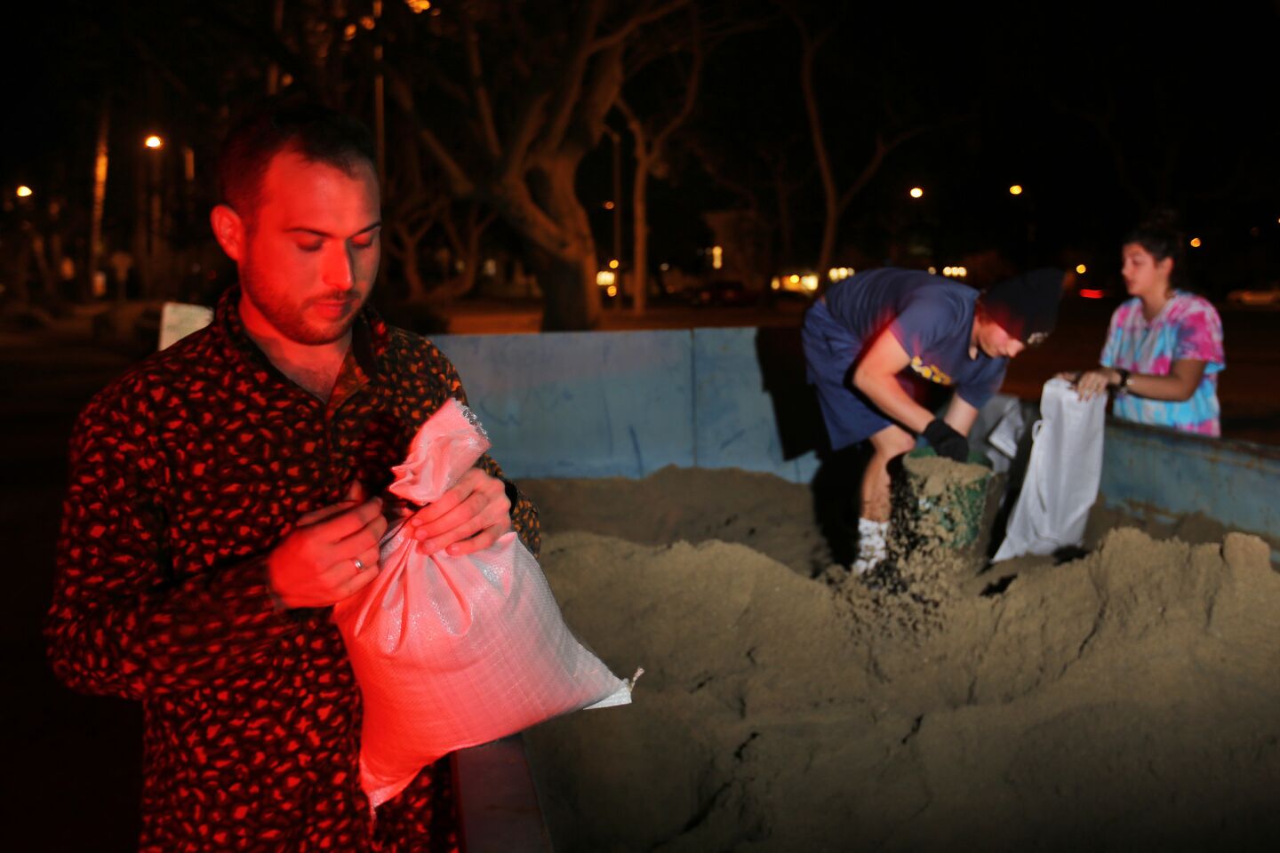 Noah Cowan of Long Beach, fills sandbags along with others as they prepare for the arrival of the first major storm of what is expected to be a strong El Niño weather event in Southern California.