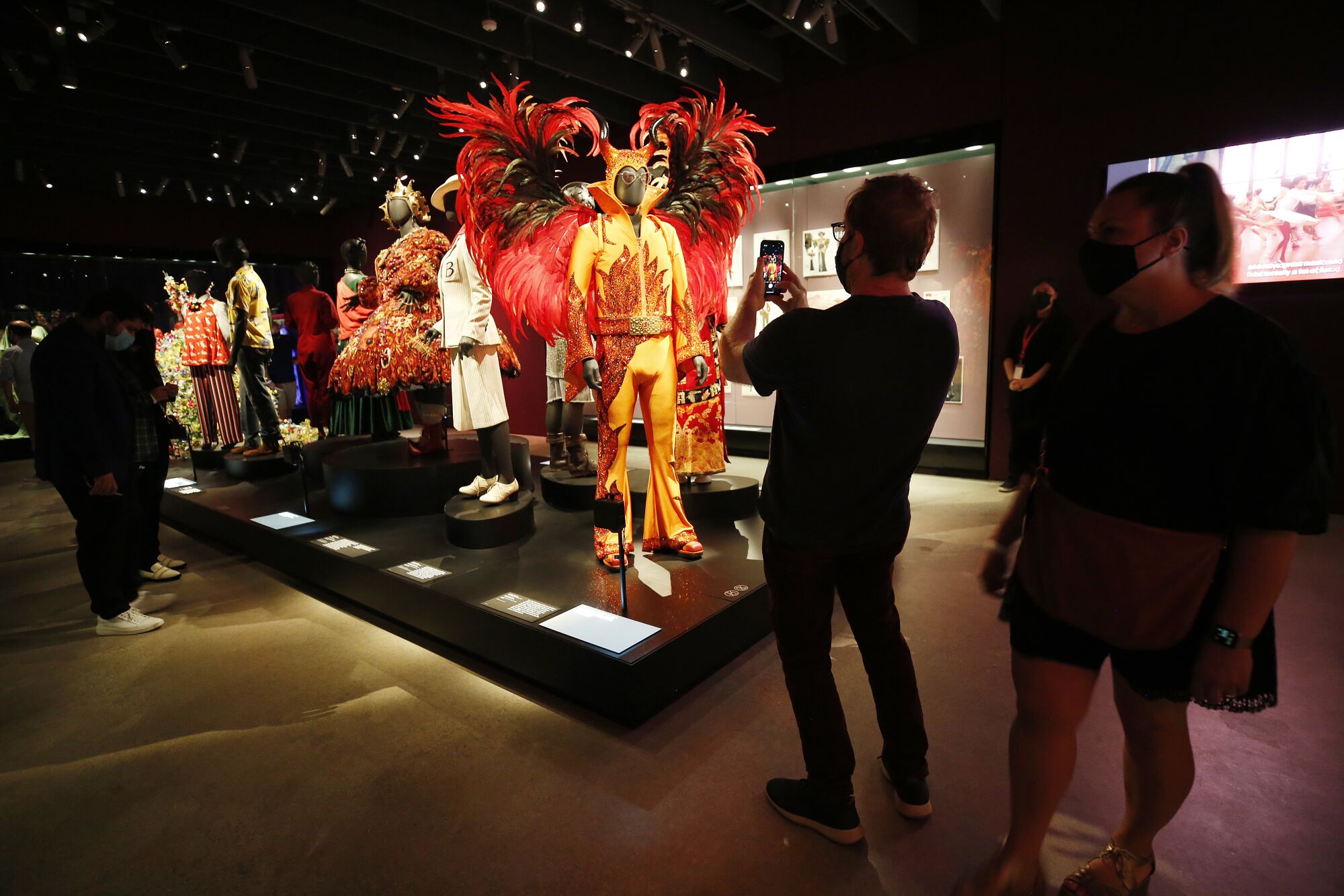 Guests take photos in the costume exhibit at the Academy Museum of Motion Pictures.