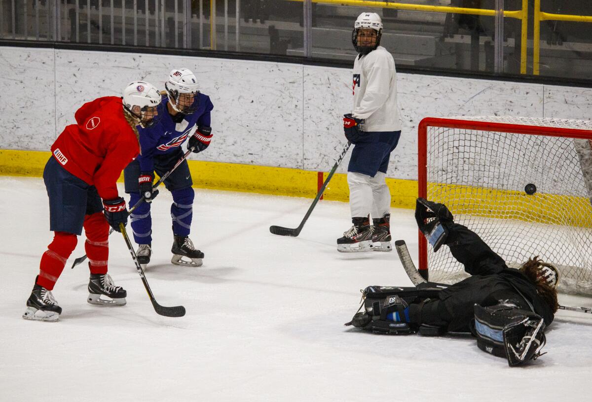 U.S. Women's hockey forward Annie Pankowski, left in red, from Laguna Hills, scores a goal as she practices with the team as they start training camp at Great Park Ice in Irvine on Wednesday.