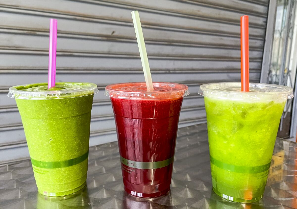 Green and red drinks, with straws sticking out of the top of the cups.