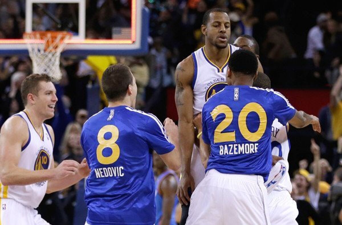 Golden State forward Andre Iguodala is lifted into the air by a teammate after hitting the game-winning shot against the Thunder as time expired Thursday night.