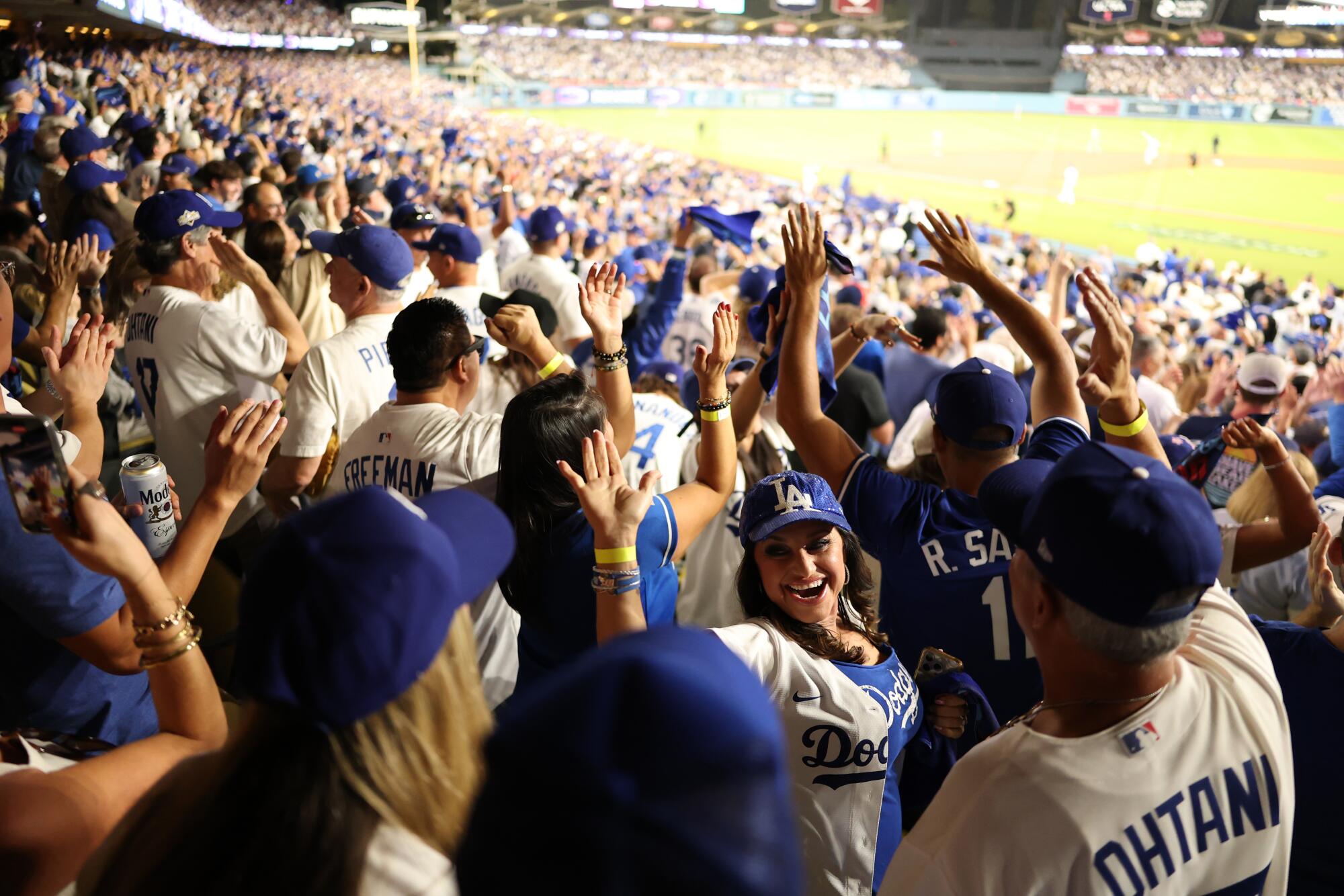 Os fãs dos Dodgers comemoram depois que Shohei Ohtani acerta o segundo de seus três home runs no jogo 4 do NLCS.