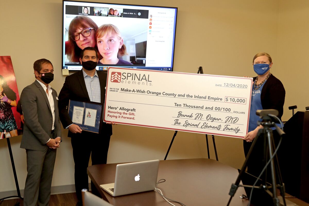 Dr. Burak Ozgur, center, presents Make-A-Wish Foundation's Angela Wise, right, with a $10,000 check.