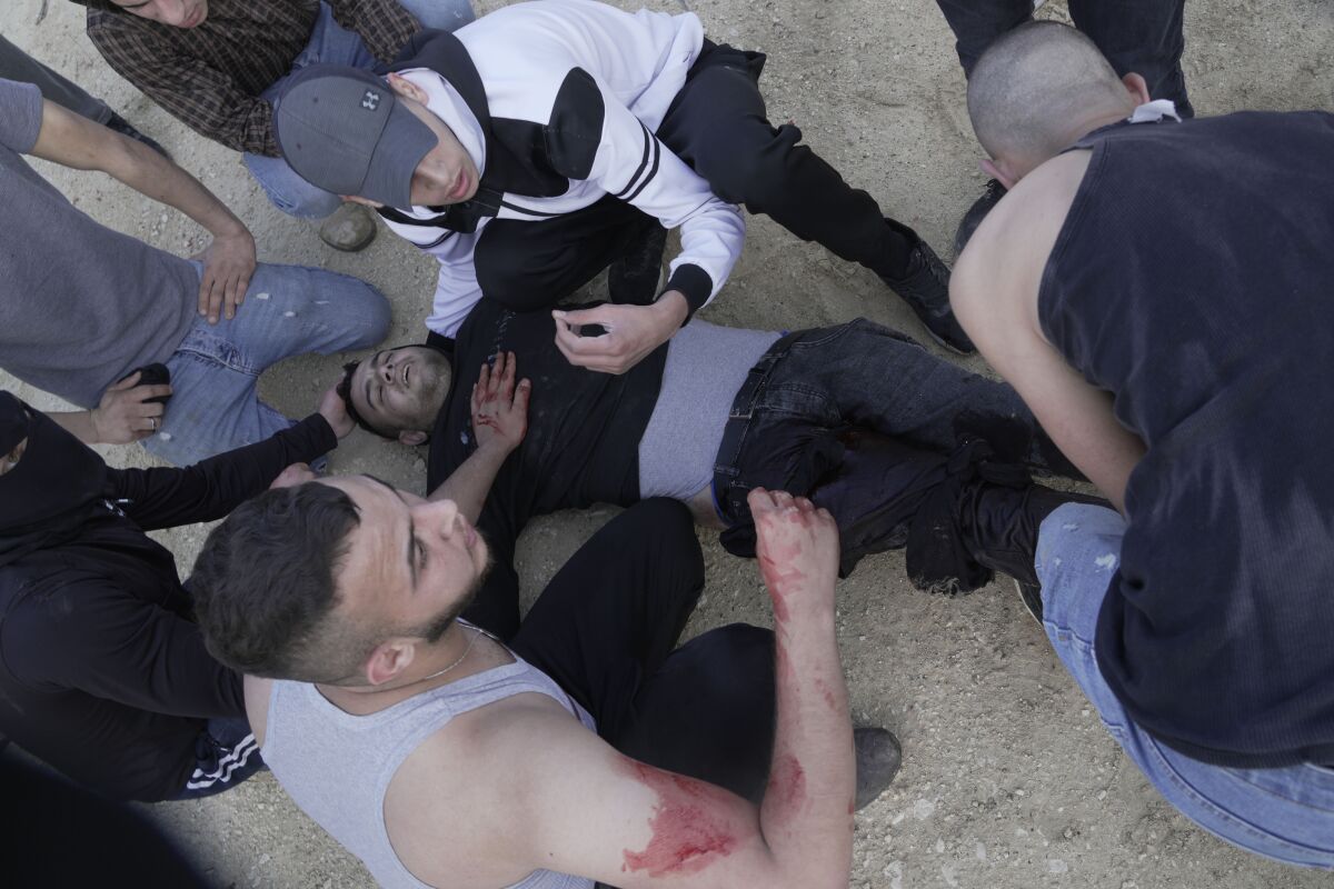 Palestinians help a wounded man during clashes with Israeli soldiers in the West Bank village of Silat al-Harithiya, near Jenin, Saturday, May 7, 2022, as Israeli forces demolished the home of Omar Jaradat was part of a group who shot and killed yeshiva student Yehuda Dimentman in the West Bank in Decemer 2021. (AP Photo/Majdi Mohammed)