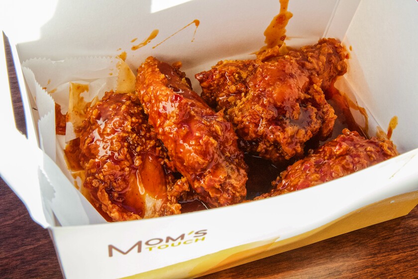 A box of heavily sauced fried chicken wings from Mom's Touch.