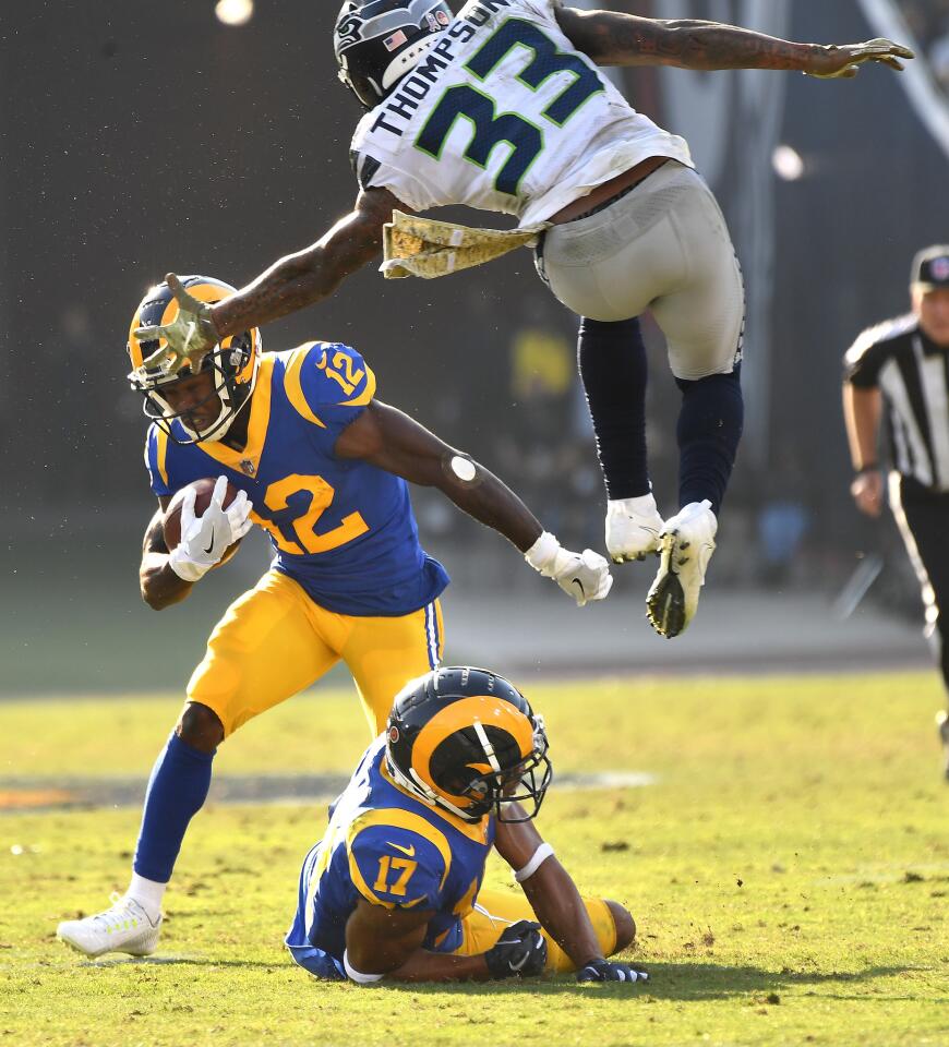 Rams receiver Brandin Cooks picks up yards as Seattle Seahawks safety Tedric Thompson leaps over receiver Robert Woods to try and make a tackle in the second quarter at the Coliseum on Sunday.
