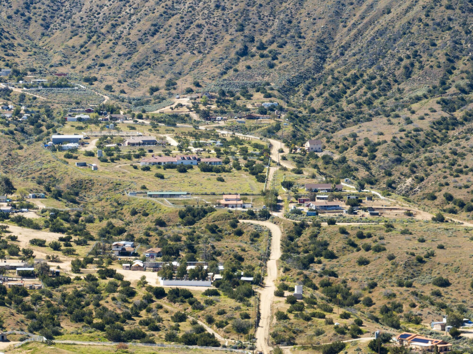 A view from above of homes and trees dotting a hilly landscape 