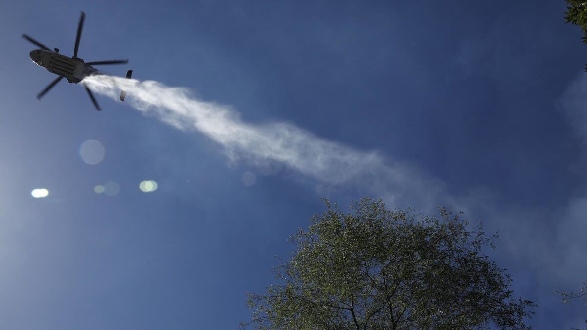 A helicopter drops water on a fire at the end of Portola Drive in the Benedict Canyon area.