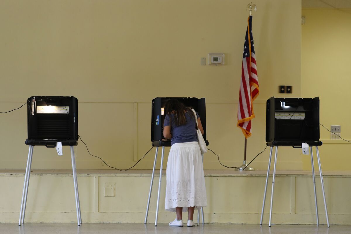Gissele Riberiro fills out her ballot as she votes at the Legion Park.