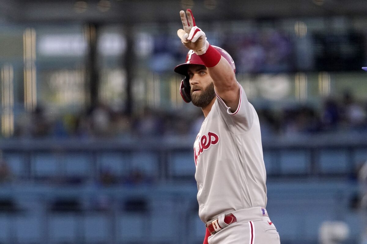 Philadelphia's Bryce Harper gestures toward his dugout after hitting a double during the first inning Saturday.