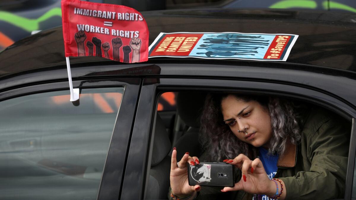 Olimpia Blanco records video a convoy of tractor-trailers staging a protest at the Metropolitan Detention Center in Los Angeles.