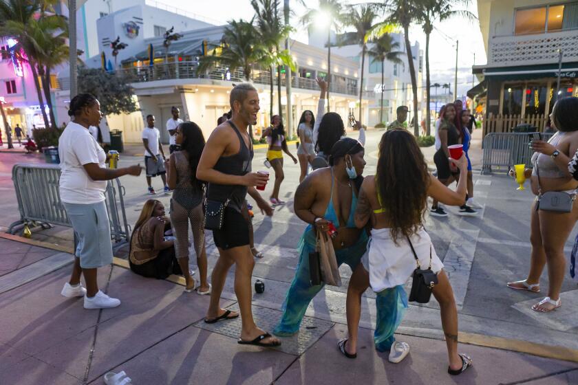 A group of tourists dance on Ocean Drive during Spring Break in Miami Beach, Fla., Monday, March 22, 2021. A party-ending curfew is in effect in Miami Beach, imposed after fights, gunfire, property destruction and dangerous stampedes broke out among huge crowds of people. The curfew could extend through the end of spring break.(Matias J. Ocner/Miami Herald via AP)