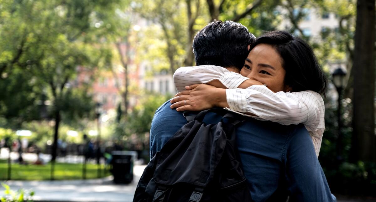 A woman hugs a man around the neck in a scene from "Past Lives."