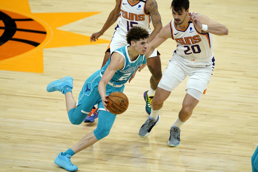 Hornets guard LaMelo Ball drives past Suns forward Dario Saric.