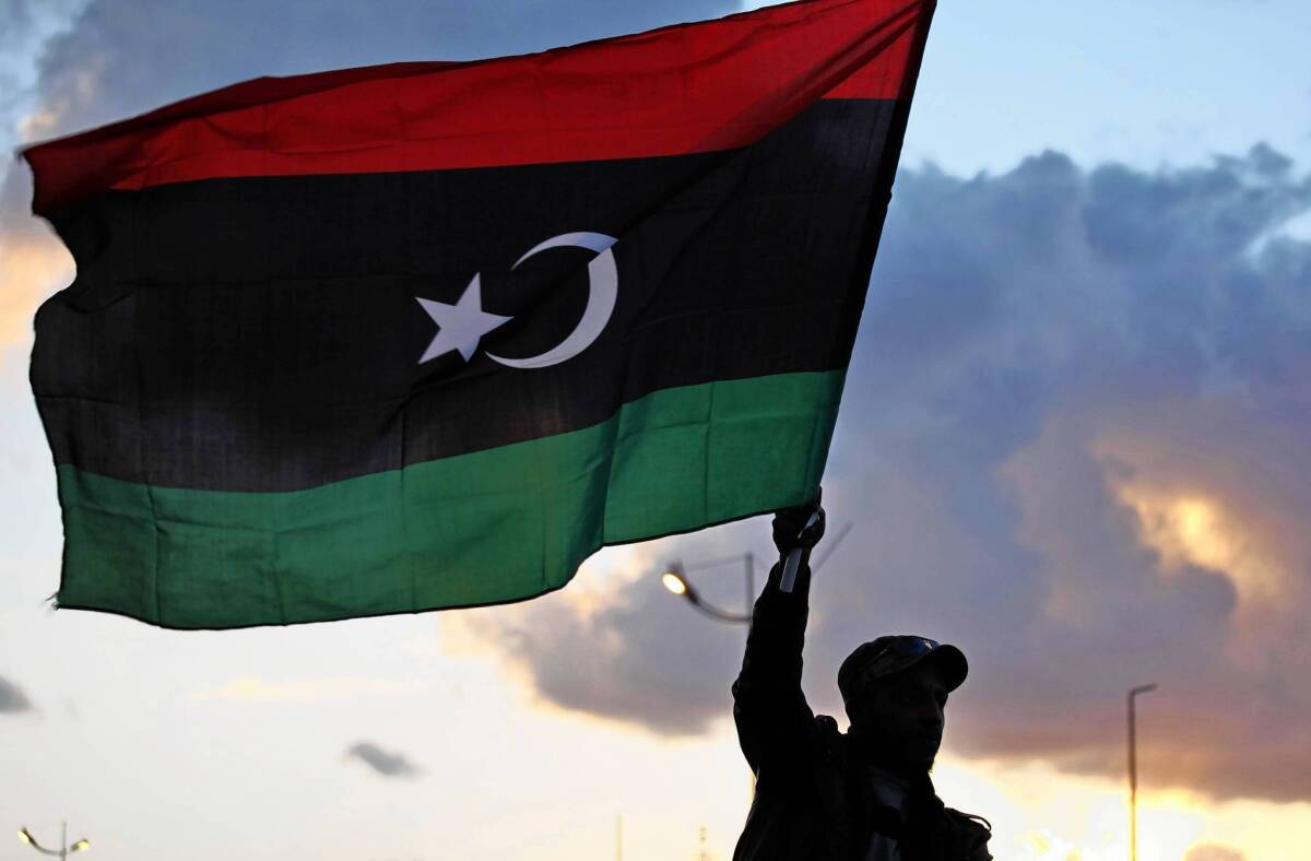 A celebrant in Benghazi, Libya, waves the national flag a commemoration of the second anniversary of the revolution that drove Moammar Kadafi from power. A weak post-Kadafi central government has left a security vacuum in the country's isolated south.