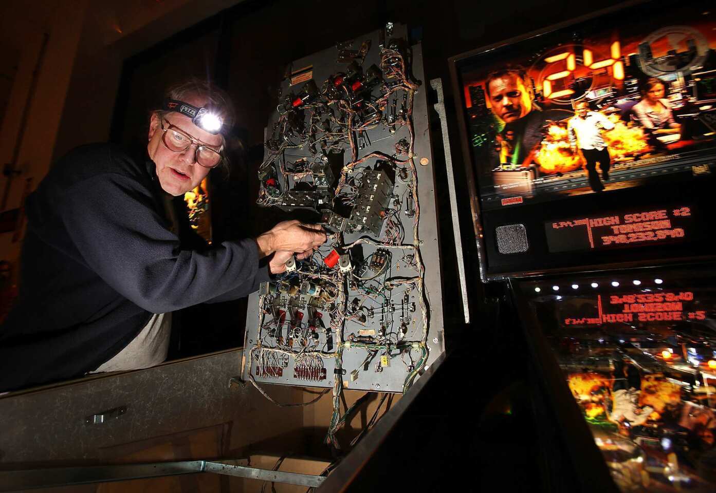 Tim Arnold, owner of the Pinball Hall of Fame, opens one of his vintage machines to make a repair.