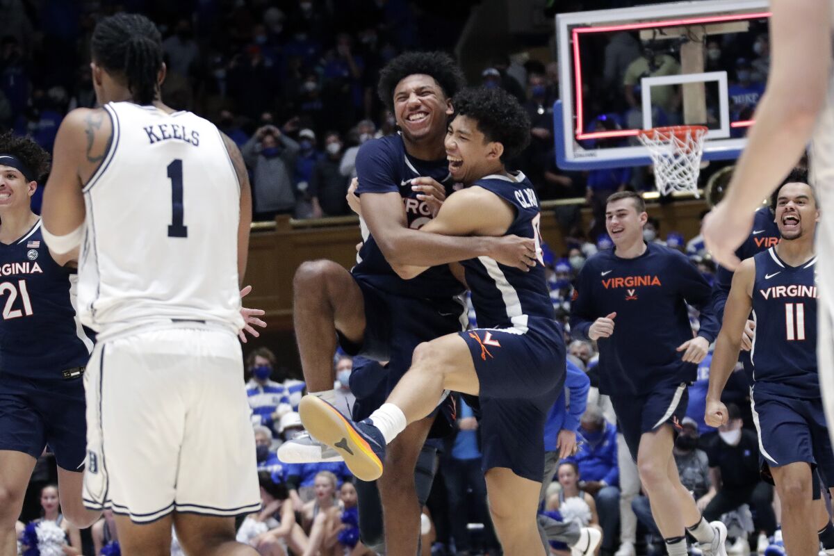 Virginia guard Reece Beekman, center left, celebrates with guard Kihei Clark (0) while Duke guard Trevor Keels (1) looks on as the clock runs out at the end of an NCAA college basketball game against Duke, Monday, Feb. 7, 2022, in Durham, N.C. Beekman hit a 3-point shot with under three seconds for the go-ahead and eventual game-winning points. (AP Photo/Chris Seward)