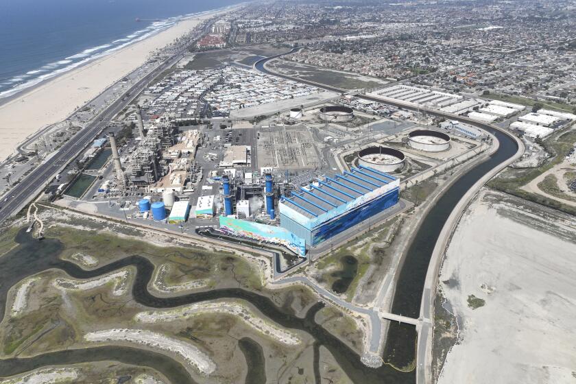 Huntington Beach, CA - April 5: An aerial view of the Talbert Channel cutting between the proposed Magnolia Tank Farm Lodge, restaurants, right, the Huntington Beach Wetlands, left, the Huntington Beach Energy Center, formerly AES Huntington Beach, a natural gas-fired power station that uses the power plant's existing ocean cooling pipes to tap the Pacific, the proposed Poseidon desalination plant, which would be built on the power plant property, and surrounding residential properties, Edison Community Park, ASCON toxic superfund cleanup sight, upper right. Photo taken Tuesday, April 5, 2022. The partially retired Huntington Beach Generating Station consists of four generating units but only unit 2 is still in commercial operation as a legacy unit and has an extension to operate through the end of 2023, issued by the California State Water Boards. Unit 2 runs to support peak demands and has a net output capacity of 225 megawatts. The 644 MW combined cycle gas turbine generator, shown in blue and white, began operation on June 25, 2020. Environmental groups have fought Poseidon, arguing that it is privatizing a public resource, has failed to adapt an old proposal to new state ocean protections from killing sea life and that the company is trying to fill a need that doesn't exist, uses too much natural gas energy. Environmental justice activists say water rates could be raised as much as $6 per month. Supporters say ocean desalination as an inexhaustible, local supply for a region that imports much of its water from increasingly unreliable, distant sources. Another stumbling block for Poseidon is state requirements to mitigate the project's harm to the marine environment. Poseidon would draw 106 million gallons a day of seawater through the huge offshore intake pipe, which would be screened, and use reverse osmosis membranes to rid the seawater of salt and impurities. That process would produce 56 million gallons a day of brine concentrate - roughly twice as salty as the ocean - which would be dumped back into the Pacific via a 1,500-foot discharge pipe equipped with outfall diffusers to promote mixing and dilution. The intake and discharge operations will take a toll on plankton, which plays a crucial role in the marine food chain, killing an estimated 300,000 microscopic organisms a day. (Allen J. Schaben / Los Angeles Times)