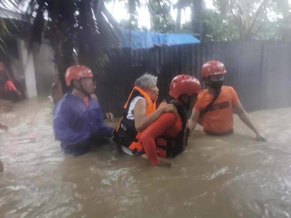 In this photo provided by the Philippine Coast Guard, rescuers evacuate residents to safer ground as floods caused by Tropical Storm Choi-wan hits Maasin City in Southern Leyte province, central Philippines on Tuesday June 1, 2021. The tropical storm has left at least a few people dead and displaced hundreds of villagers in the southern and central Philippines, where it set off flooding and landslides, officials said Wednesday. (Philippine Coast Guard via AP)