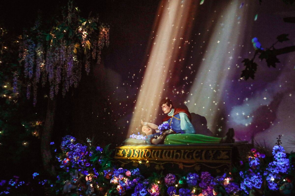 Lights shine on a sleeping woman as a prince leans over to kiss and wake her.